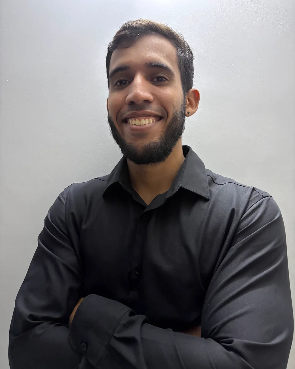 Retrato de German Flores, sonriendo, con barba corta y camisa negra.
